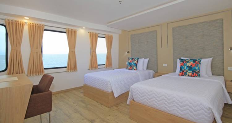 Tweepersoonsslaapkamer met zeezicht op een jacht.