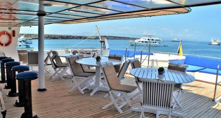 Upper deck seating area with tables, chairs and sea views on a sunny day.