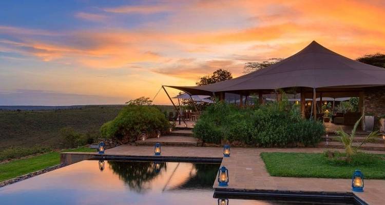 Luxuriöse Lodge mit Infinity-Pool bei Sonnenuntergang.