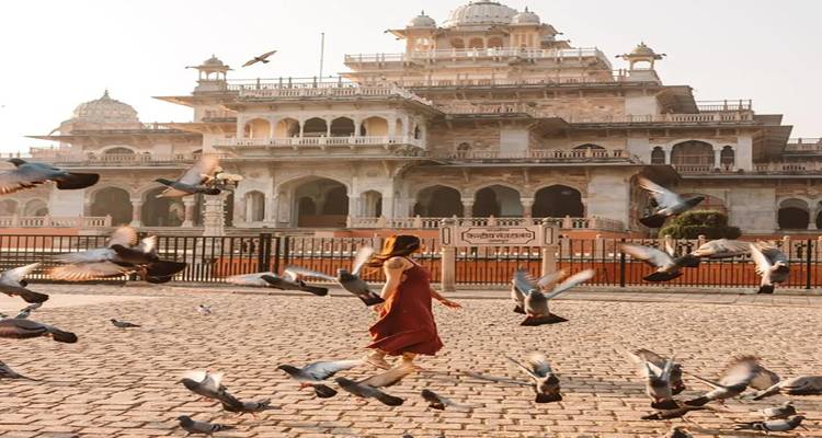 Kind läuft zwischen Tauben vor einem historischen Gebäude.