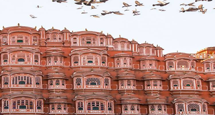 Intricately designed facade of Hawa Mahal with birds flying above