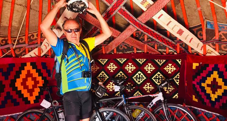 Cyclist standing beside bikes in a vibrantly decorated room.