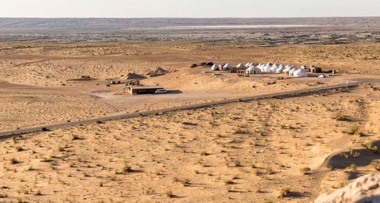 Wide desert landscape with scattered tents and buildings.