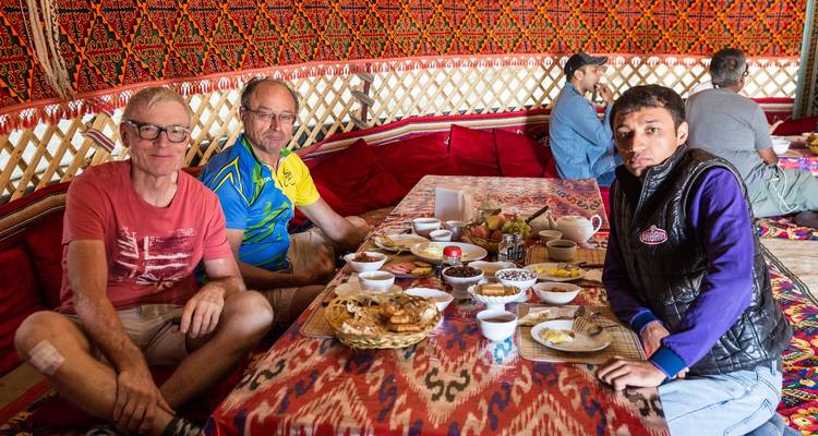 Group of people sitting and enjoying a meal inside a decorated tent.