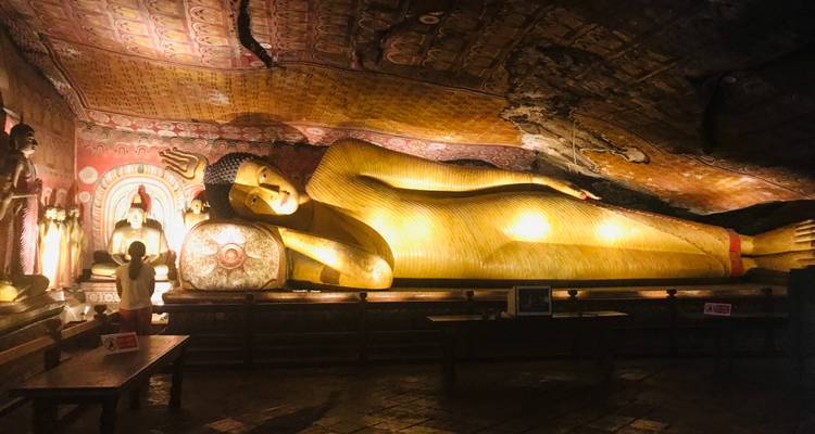Große liegende Buddha-Statue in einer schwach beleuchteten Höhle.