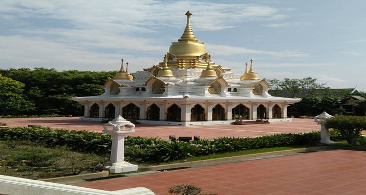 Weißer Tempel mit goldenen Türmen, umgeben von Grün.