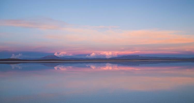 Weerspiegeling van kleurrijke wolken over een zoutvlakte