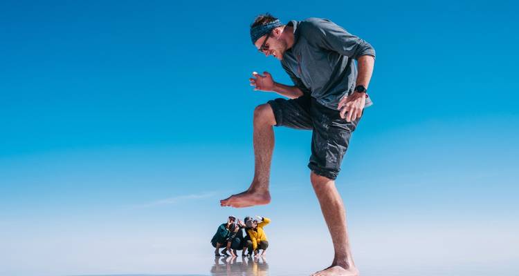 Perspectief shot van een man die speels poseert boven een groep mensen op zoutvlaktes