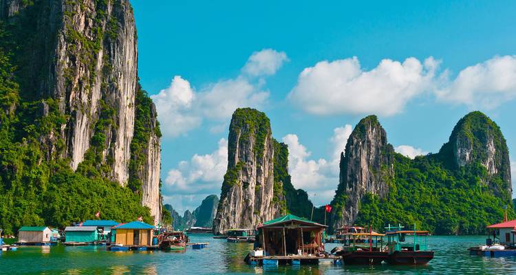 Floating fishing village with towering limestone cliffs.