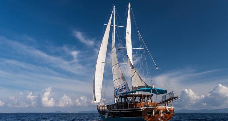 Velero navegando en el mar bajo cielos azules despejados.