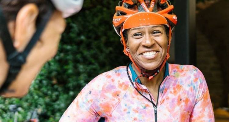 Un cycliste souriant portant un casque coloré et un maillot.