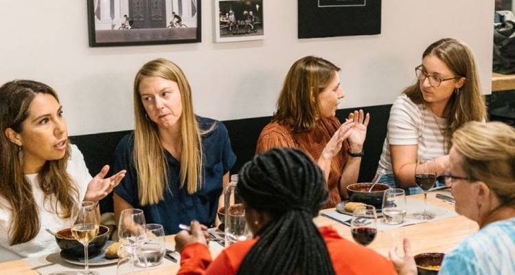 Des personnes assises autour d'une table prenant un repas et conversant à l'intérieur.