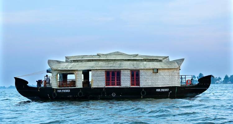 Traditionelles Hausboot mit hölzernem Dach schwebt auf ruhigen Backwaters unter einem blassen Himmel