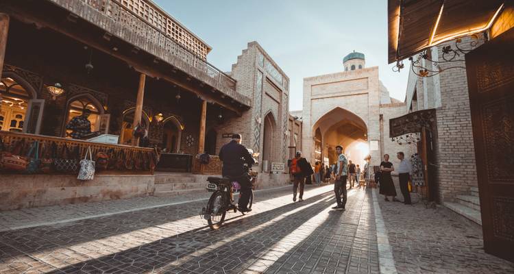 A lively street scene with a cyclist, traditional buildings, and people walking.