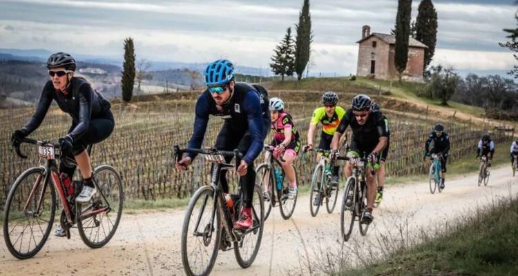 Cyclists riding through vineyards with a historic church.