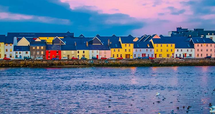 Kleurrijke huizen aan het water in Galway die de schemering kleuren op het wateroppervlak weerspiegelen.