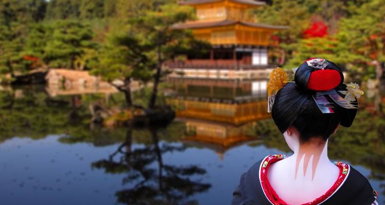 Back view of a geisha in elegant kimono gazing at the Golden Pavilion reflected in a tranquil pond.