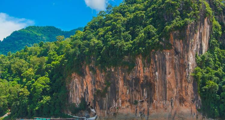 Malerische Aussicht auf eine große Klippe mit dichter Vegetation unter einem klaren blauen Himmel.