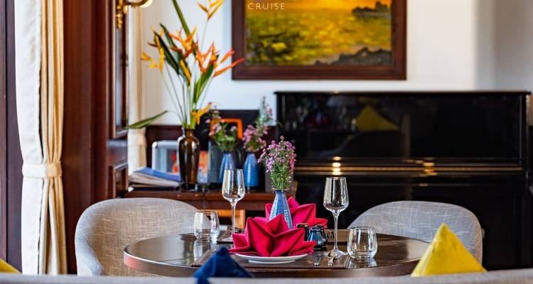 Tafel gedekt met bloemen en glaswerk in een eetzaal van een cruiseschip.