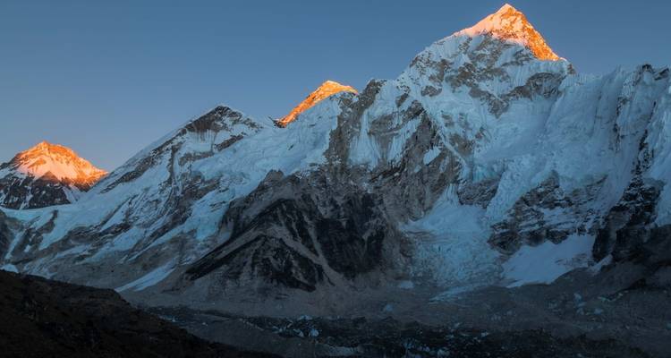Schneebedeckte Berge unter einem klaren Himmel bei Sonnenuntergang.