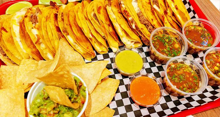 Un plateau de tacos avec diverses sauces servies en accompagnement.