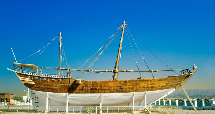 Traditionelles Holzsegelboot in Ausstellungsposition vor klarem blauem Wüstenhimmel.
