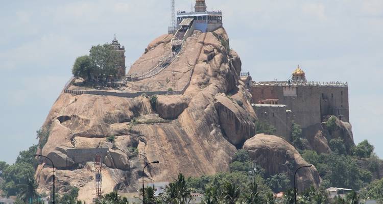 Colline rocheuse avec d'anciens temples construits dessus sous un ciel bleu.