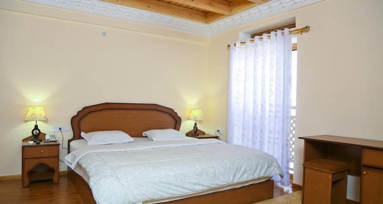 Einfaches Hotelzimmer mit einem Kingsize-Bett und Holzmöbeln.