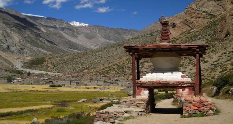 Stupa mit Bergkulisse und einem Dorf.