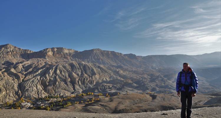 Person, die auf einem Grat steht und eine Berglandschaft überblickt.