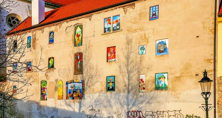 Muur met kleurrijke artistieke tekeningen en schaduwen van bomen.