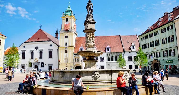 Mensen die rond een fontein zitten op een oud plein.