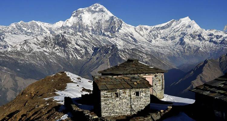 Besneeuwde berg met een stenen gebouw op de voorgrond.