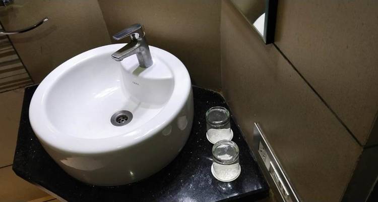 Nahaufnahme eines modernen Badezimmerwaschbeckens mit zwei Gläsern und Toilettenartikeln.