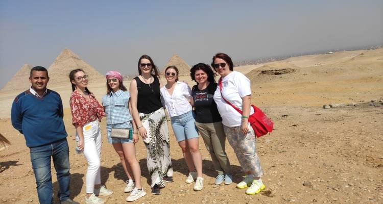 Een groep mensen met de Piramides van Gizeh op de achtergrond.