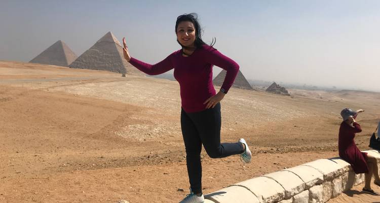Een persoon die speels poseert bij de piramides.