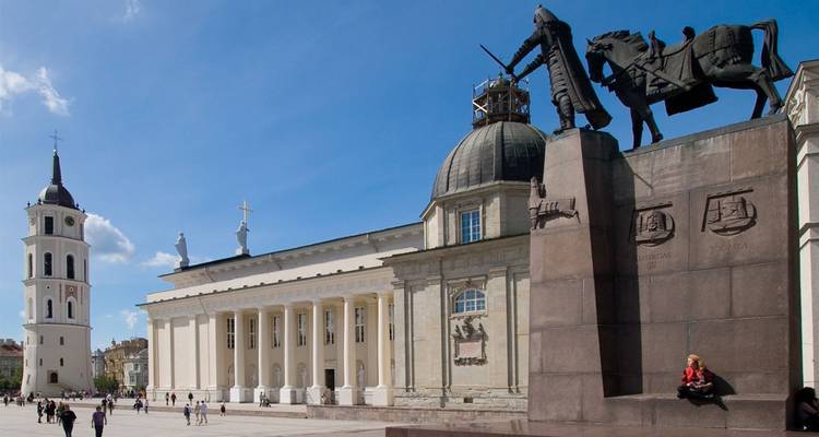 Vilnius Cathedral Square with the bell tower and equestrian statue under blue skies.