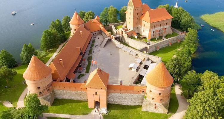 Aerial view of red-roofed Trakai Island Castle surrounded by blue lake waters.
