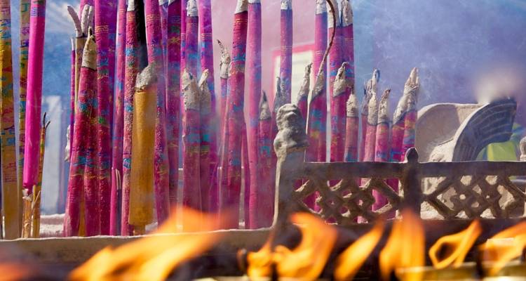 Bâtons d'encens qui brûlent avec une structure en pierre au premier plan.