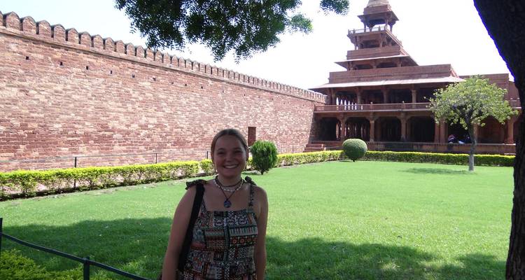 A smiling traveller poses beside manicured lawns and the multi-tiered Panch Mahal pavilion