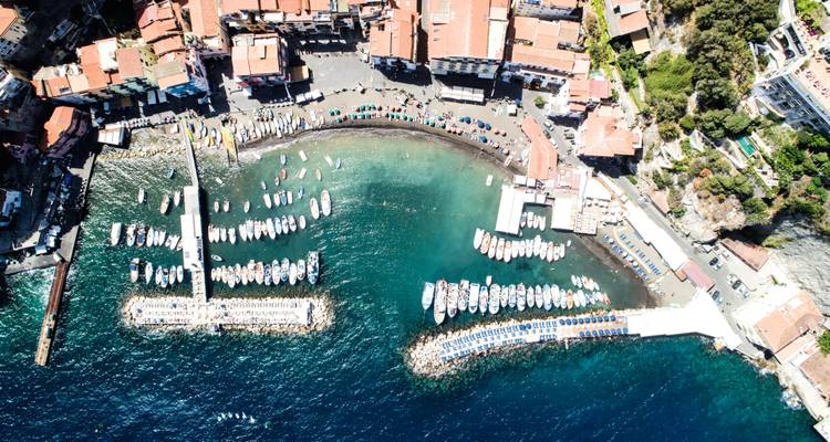 Vue aérienne par drone d'une marina avec bateaux et eaux turquoise le long de la côte de Sorrente.