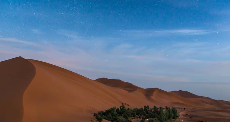 Een woestijnlandschap met een duin en een sterrenhemel.