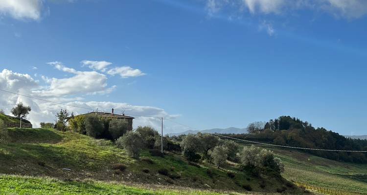 Weelderig landelijk uitzicht met heuvels en een stenen huis.