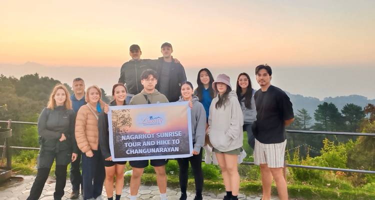 Group of people posing with a banner at sunrise.