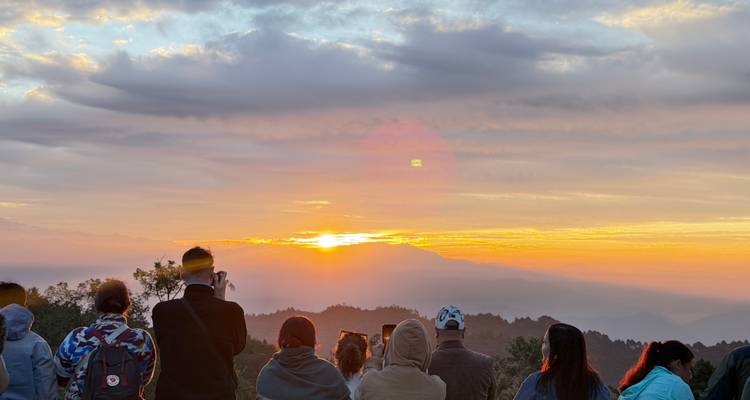 People watching the sunrise over mountains.