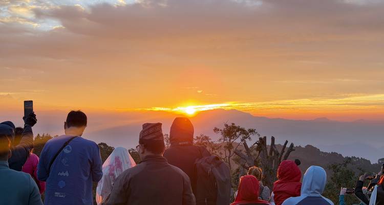 Crowd watching the sunrise with mountains in the distance.