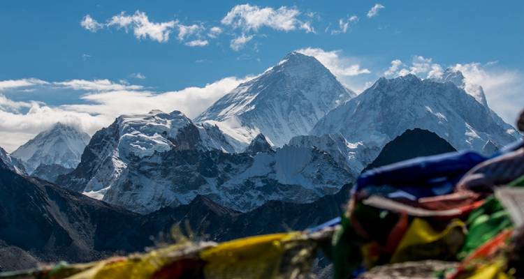 Nahaufnahme von schneebedeckten Bergen mit Gebetsfahnen im Vordergrund.