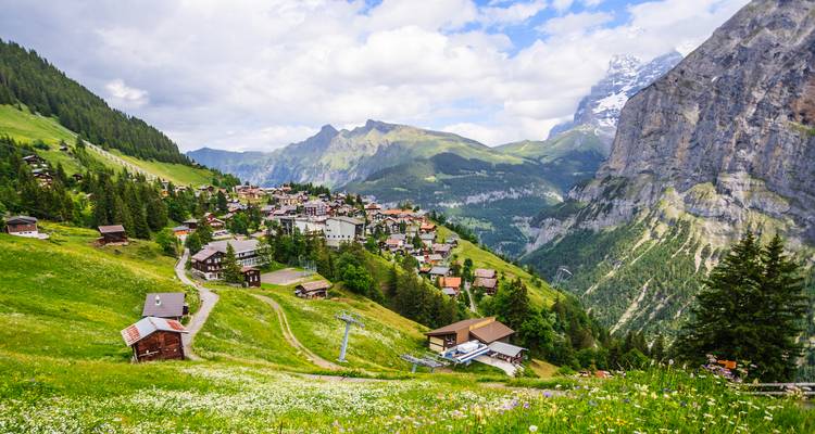 Charming alpine village of Mürren perched on steep green slopes with towering peaks