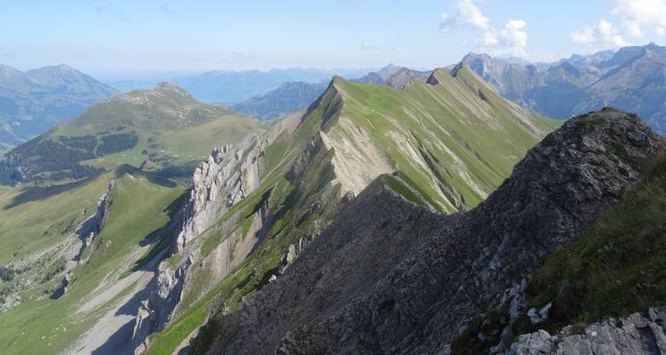 Rugged alpine ridge line with steep grassy slopes under a clear blue sky