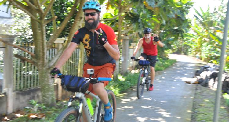Radfahrer, die schnell einen Weg entlangfahren, mit Bäumen und Pflanzen, die die Strecke säumen.